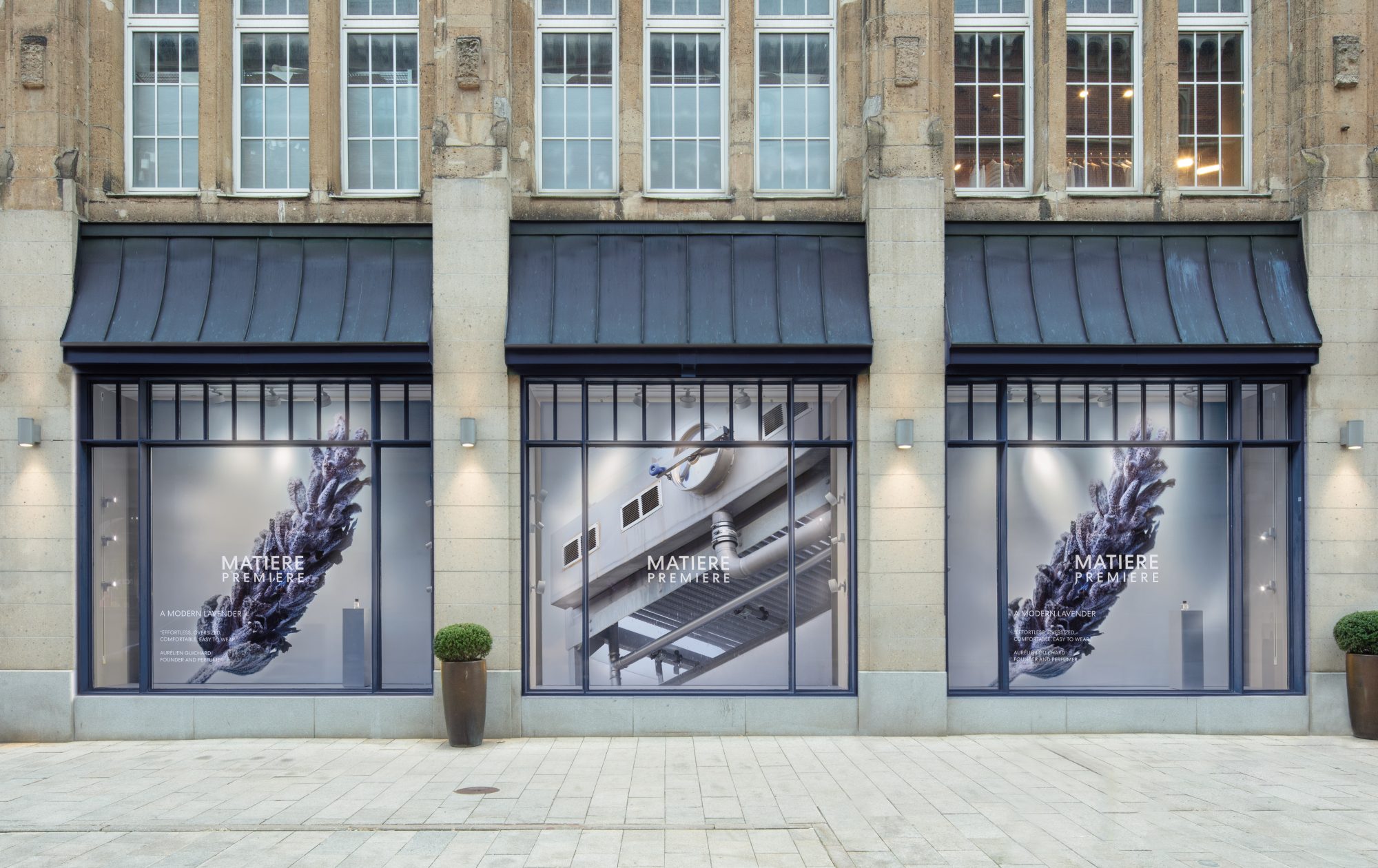 Drei MATIERE PREMIERE Schaufenster mit Lavendel- und Rohstoffmotiven unter dunklen Markisen.