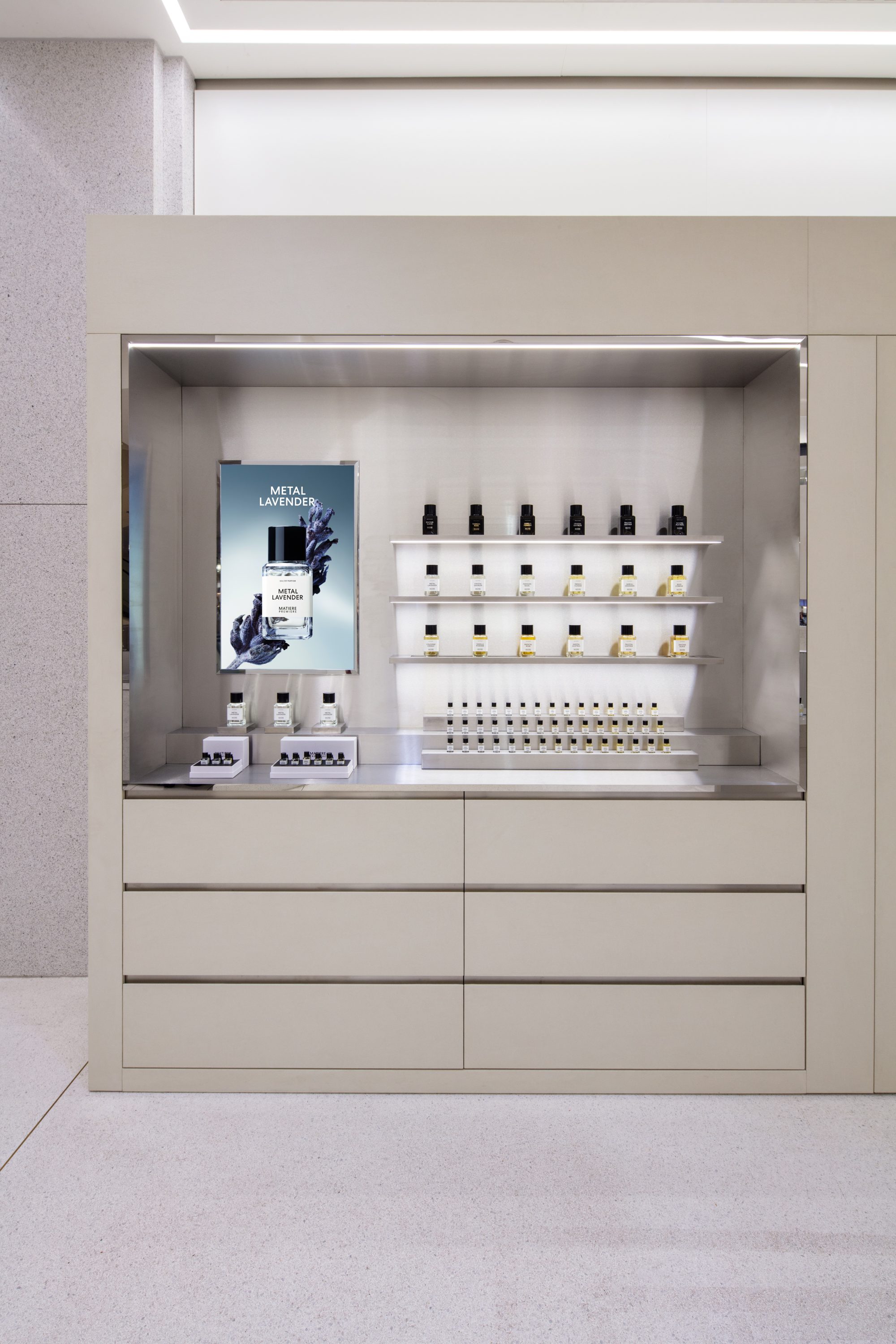 Wanddisplay mit Parfumflakons, Duftproben und einem Metal-Lavender-Kampagnenmotiv.